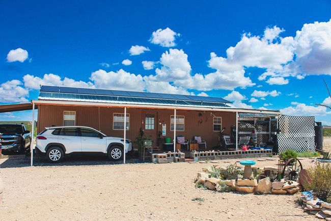 Back of house featuring roof mounted solar panels, a metal roof, and a carport | Image 12