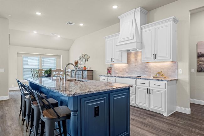 Kitchen with an island with sink, dark wood finished floors, decorative backsplash, light stone countertops, and recessed lighting | Image 9