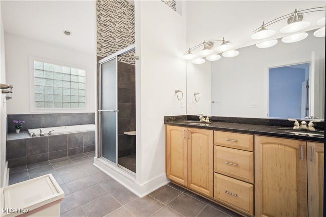 Full bathroom with tile patterned flooring, a shower stall, a garden tub, double vanity, and a sink | Image 18