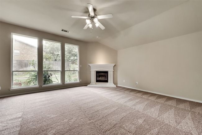 Unfurnished living room with carpet flooring, ceiling fan, a glass covered fireplace, and vaulted ceiling | Image 18