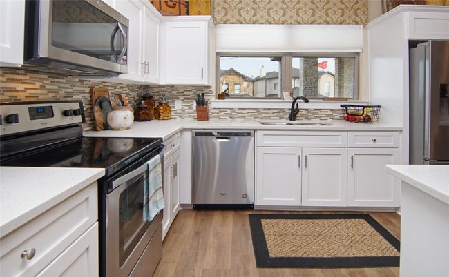 Kitchen featuring appliances with stainless steel finishes, white cabinets, and backsplash | Image 9