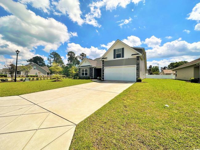 View of front of property featuring a front yard, an attached garage, stone siding, board and batten siding, and driveway | Image 21