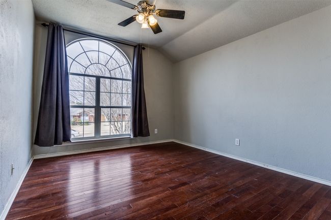 Spare room featuring lofted ceiling, hardwood / wood-style floors, baseboards, ceiling fan, and a textured wall | Image 18