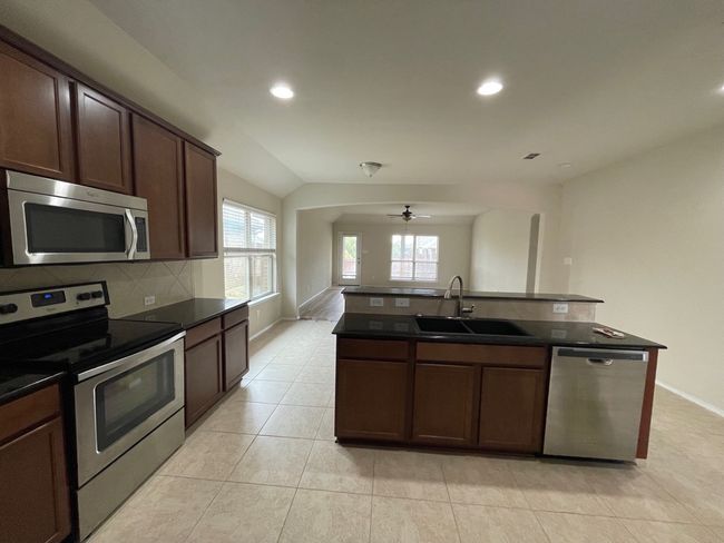Kitchen with appliances with stainless steel finishes, dark countertops, a ceiling fan, tasteful backsplash, and recessed lighting | Image 19