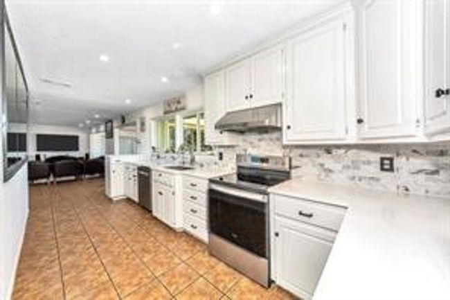 Kitchen with stainless steel appliances, under cabinet range hood, white cabinetry, and recessed lighting | Image 14