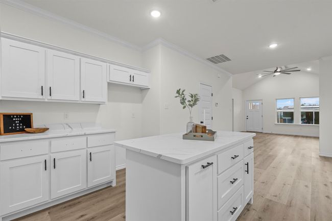 Kitchen with a center island, ornamental molding, and white cabinets | Image 20