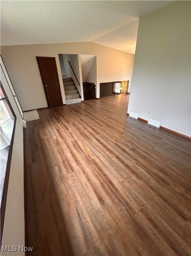 Unfurnished living room featuring stairway, wood finished floors, vaulted ceiling, and baseboards | Image 8