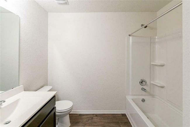 Bathroom with wood finished floors, vanity, shower / washtub combination, and a textured wall | Image 15