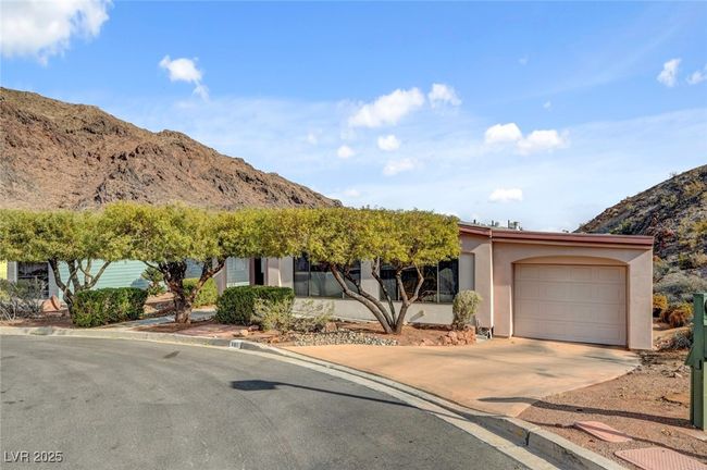 Obstructed view of property featuring concrete driveway, a mountain view, an attached garage, and stucco siding | Image 5