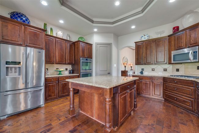 Kitchen with appliances with stainless steel finishes, arched walkways, dark wood-type flooring, backsplash, and recessed lighting | Image 17