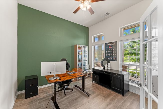 Office space with light wood finished floors, ceiling fan, and a high ceiling | Image 18