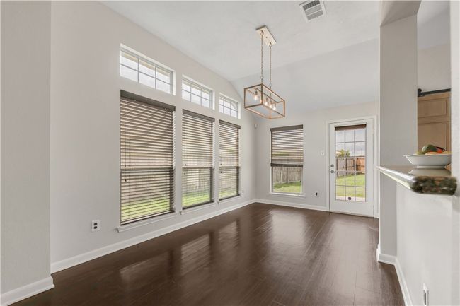 Unfurnished dining area with a chandelier, dark wood-type flooring, and baseboards | Image 6
