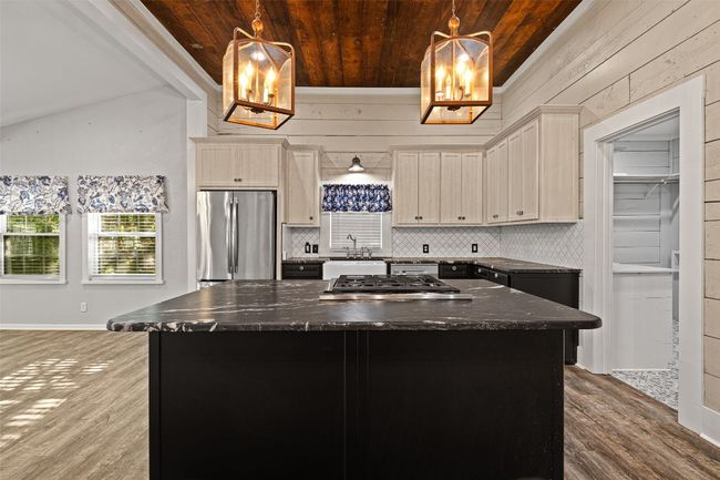 Kitchen featuring stainless steel appliances, backsplash, wood finished floors, wooden ceiling, and a kitchen island | Image 7
