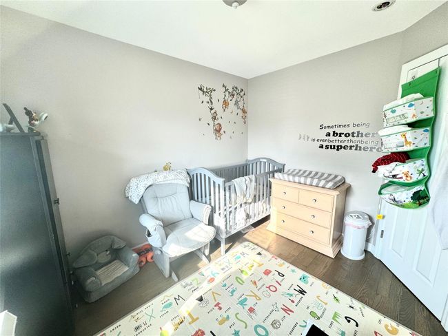 Bedroom featuring wood finished floors and a nursery area | Image 11
