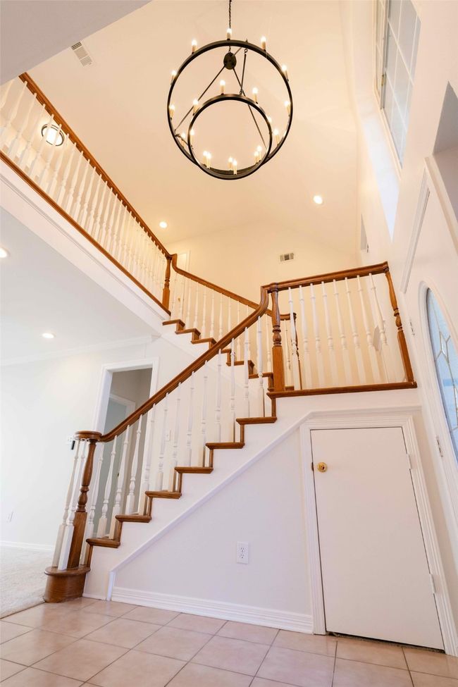 Stairs featuring a chandelier, tile patterned flooring, recessed lighting, and high vaulted ceiling | Image 9