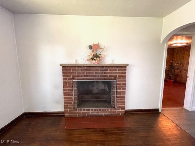 Detailed view of wood finished floors, a brick fireplace, arched walkways | Image 10