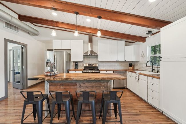 Kitchen with appliances with stainless steel finishes, wall chimney exhaust hood, a sink, a kitchen breakfast bar, and decorative backsplash | Image 10