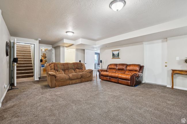 Living room featuring stairway, a textured ceiling, baseboards, and carpet | Image 38