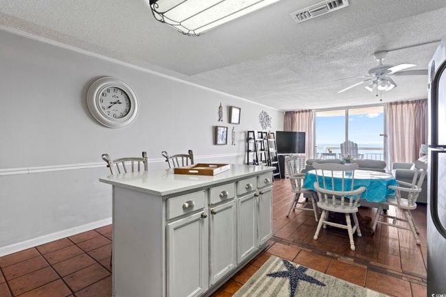 Kitchen with expansive windows, a kitchen island, a textured ceiling, visible vents, and ceiling fan | Image 16