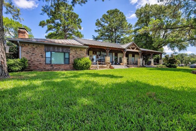 Back of property featuring a lawn, brick siding, a chimney, a standing seam roof, and covered porch | Image 10