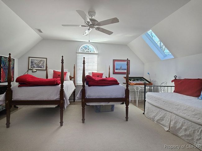 Carpeted bedroom with a ceiling fan, visible vents, and vaulted ceiling with skylight | Image 36