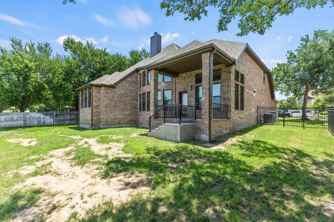 Rear view of property with brick siding, a chimney, central AC, and roof with shingles | Image 32