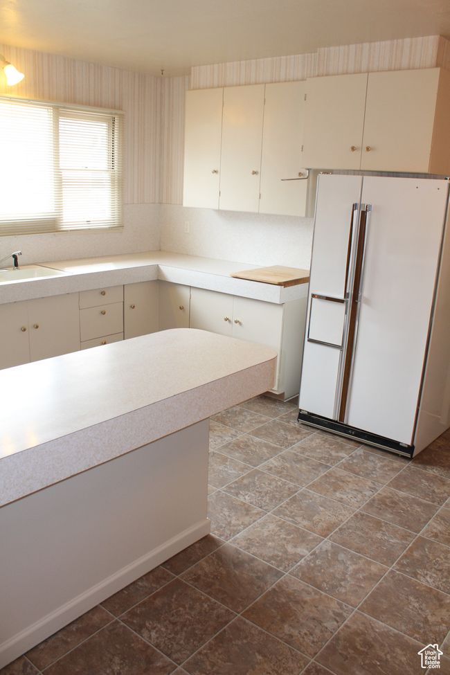 Kitchen featuring freestanding refrigerator, light countertops, and wallpapered walls | Image 7
