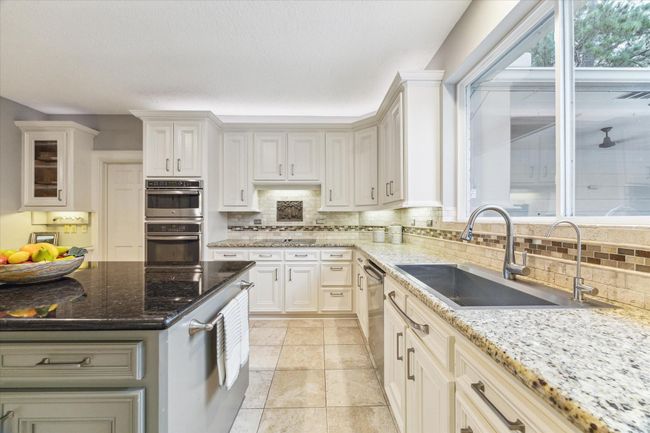 In this view of the kitchen you can see the inclusion of both practical under-counter lighting and elegant over-cabinet ambient lighting. Above the sink are large windows, which overlook the covered patio, pool, and garden. | Image 11