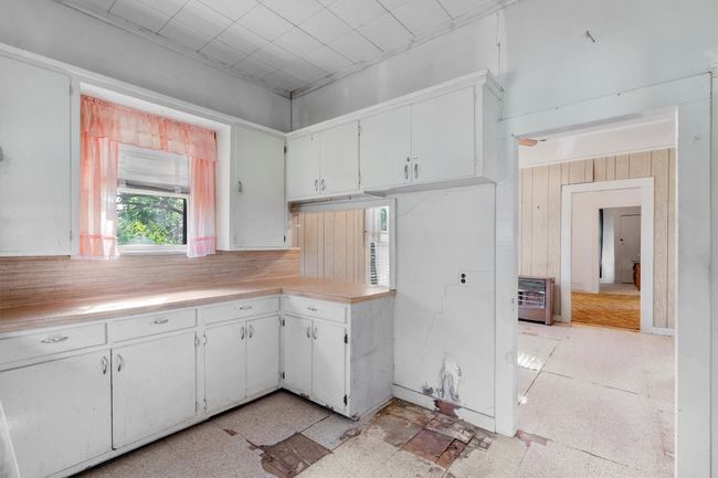 Kitchen featuring wood walls, light countertops, white cabinets, and heating unit | Image 10