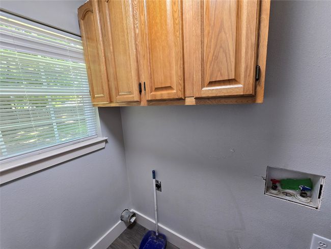 Laundry area featuring electric dryer hookup, hookup for a washing machine, and cabinet space | Image 7