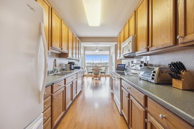 Complete kitchen with a charming breakfast nook, all set on a durable wood-patterned vinyl floor, offering functionality and a warm inviting feeling. | Image 13