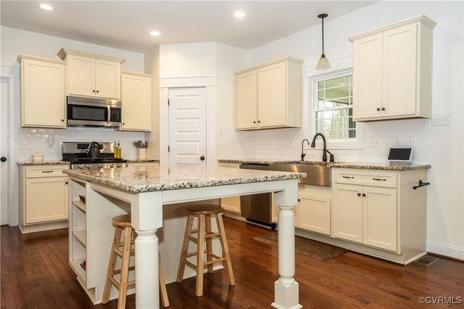 Kitchen featuring dark wood finished floors, cream cabinets, a sink, and stainless steel appliances | Image 11