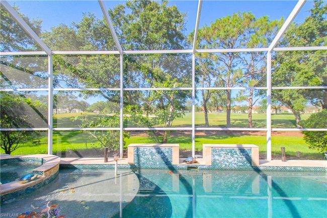 View of swimming pool featuring a patio, glass enclosure, and an in ground hot tub | Image 12