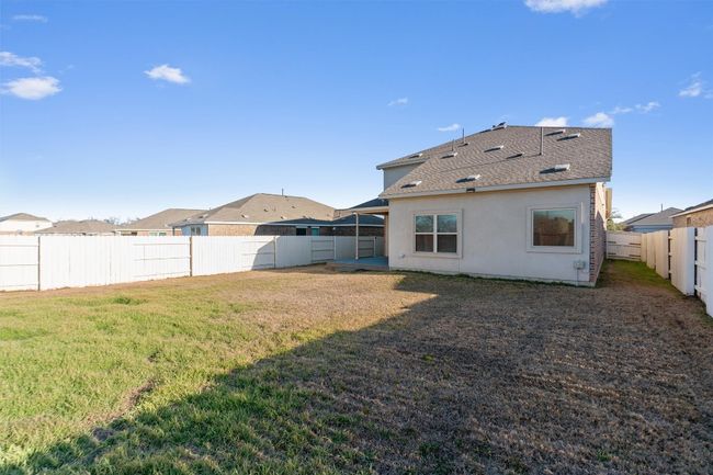 Rear view of house featuring a shingled roof, a fenced backyard, a lawn, and stucco siding | Image 37