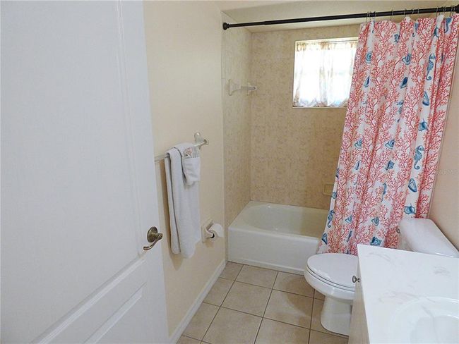 guest bathroom with combo tub and shower all tiled up to ceiling | Image 55