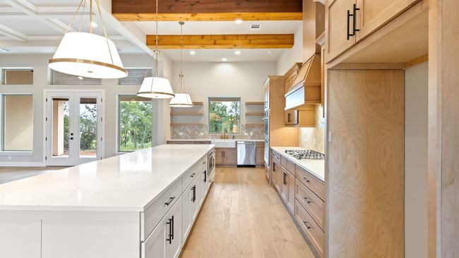 Kitchen with hanging light fixtures, light wood-type flooring, light stone counters, backsplash, and beamed ceiling | Image 15