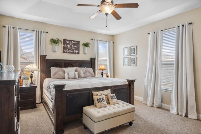 Bedroom featuring a raised ceiling, light carpet, ceiling fan, and baseboards | Image 15