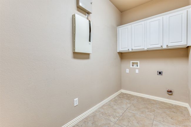 Utility Room with hookup for an electric dryer, hookup for a washing machine, cabinet space, and light tile patterned flooring | Image 23