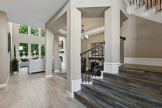 Foyer featuring cermamic wood like tile, stairs with LVP, looking into what could be dining or sitting area as well ss the living room | Image 5