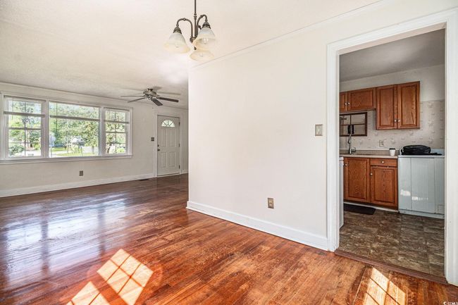 Unfurnished dining area featuring dark wood-style flooring, a chandelier, a ceiling fan, crown molding, and washer / dryer | Image 9