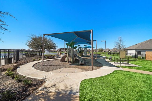 This photo showcases a community playground with slides and climbing structures, shaded by a canopy. It's surrounded by well-maintained pathways and green space, offering a family-friendly environment in a residential neighborhood. | Image 24