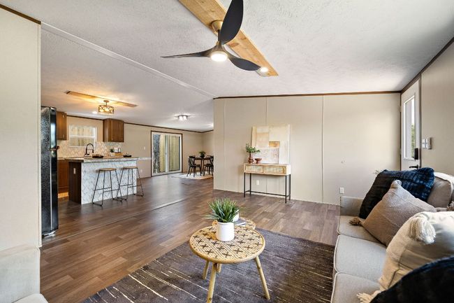 Living area featuring dark wood finished floors, a textured ceiling, a ceiling fan, and ornamental molding | Image 14