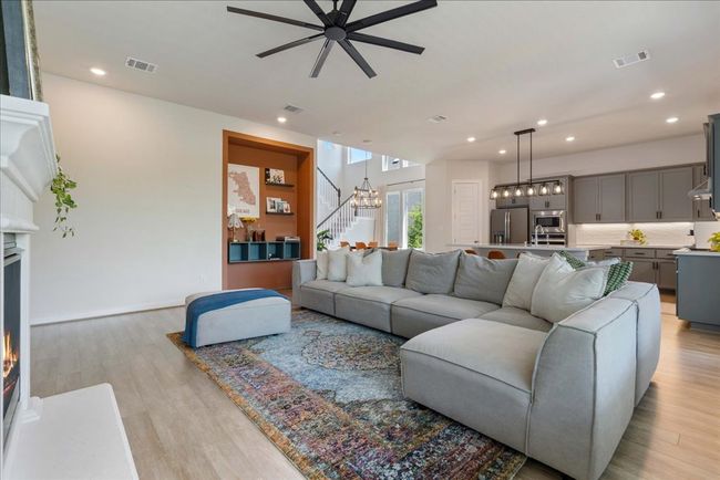 Living area featuring visible vents, light wood-style flooring, and ceiling fan with notable chandelier | Image 12