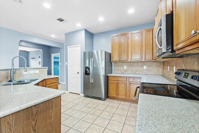 Kitchen featuring arched walkways, stainless steel appliances, light tile patterned flooring, tasteful backsplash, and recessed lighting | Image 14