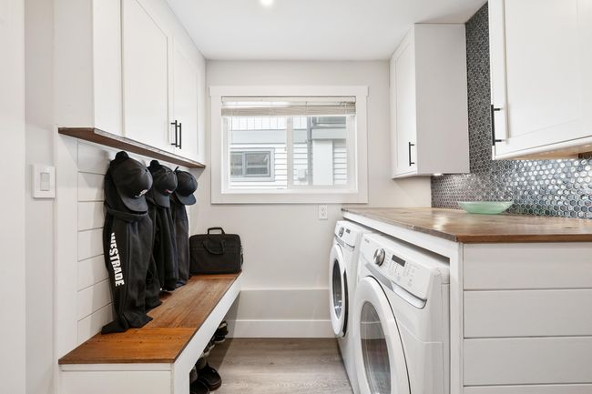 Clothes washing area featuring washer and dryer, light wood finished floors, baseboards, and cabinet space | Image 29