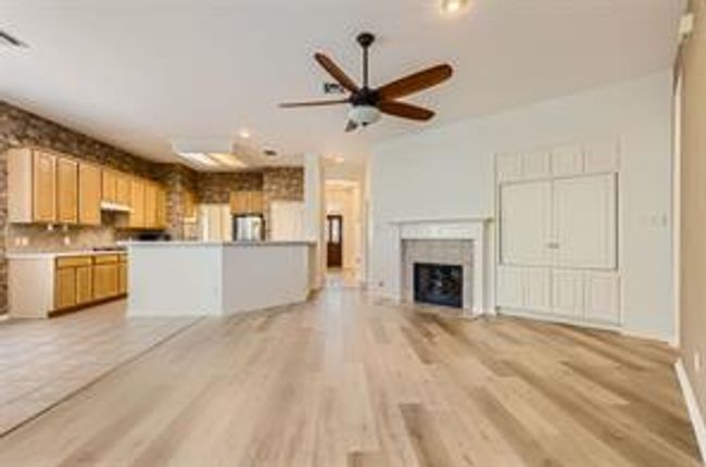 Unfurnished living room with light wood-style flooring, a fireplace, and a ceiling fan | Image 9