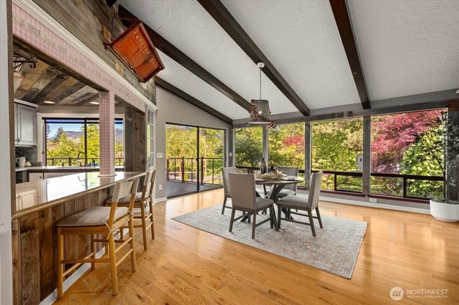Large windows showcase the view and bathe the room in natural light. Breakfast nook and kitchen eating area. A second oversized glass sliding door on the main leads to the expansive deck. | Image 15