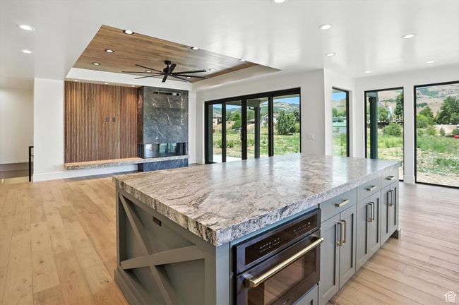 Kitchen featuring recessed lighting, gray cabinetry, a raised ceiling, a center island, and light wood-style flooring | Image 10