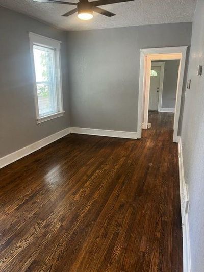 Unfurnished room featuring dark hardwood / wood-style flooring, ceiling fan, and a textured ceiling | Image 2