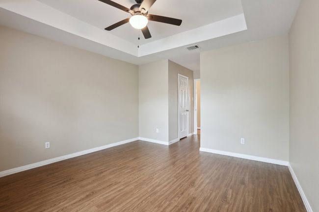 Unfurnished room with dark wood finished floors, baseboards, visible vents, a ceiling fan, and a tray ceiling | Image 28